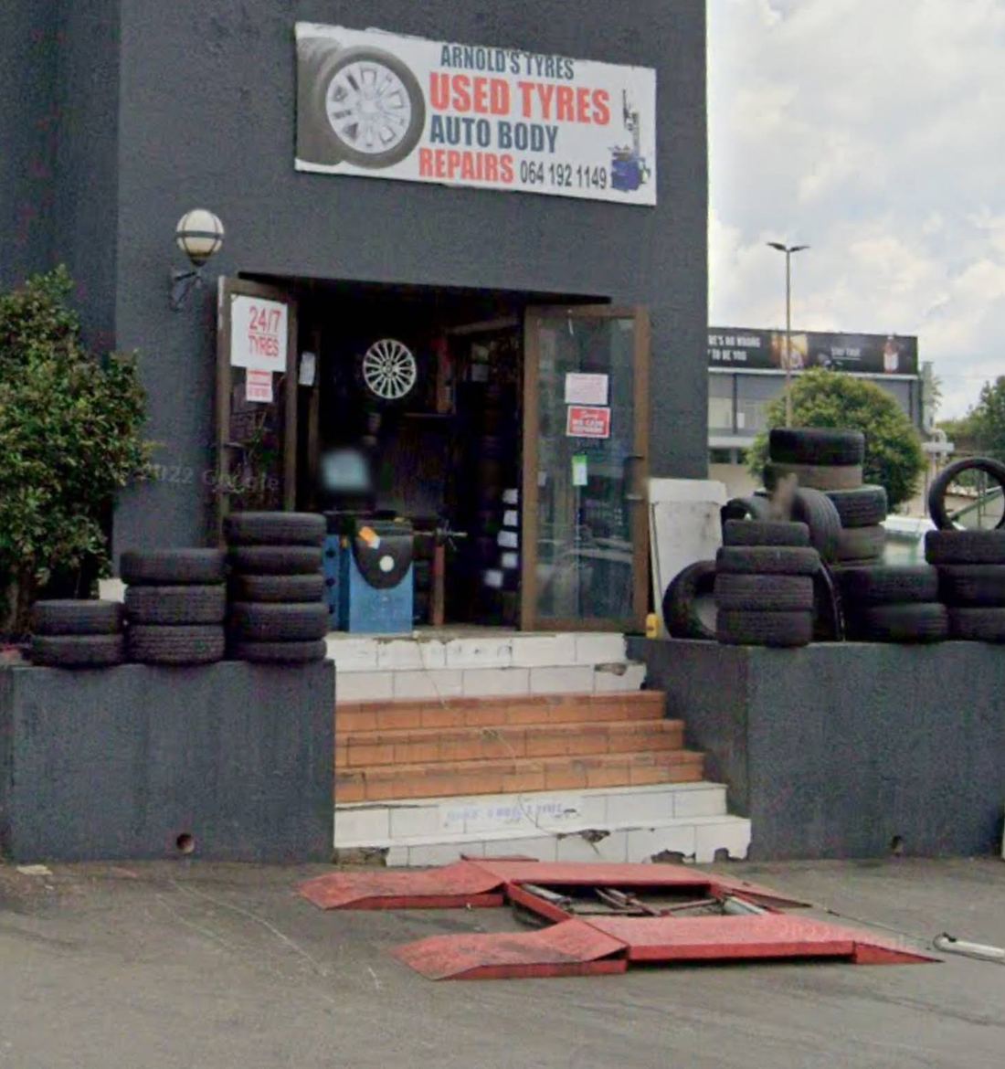 Arnold's Tyres shopfront on Jan Smuts Avenue with stacks of used tyres and a 24/7 Tyres sign on the door